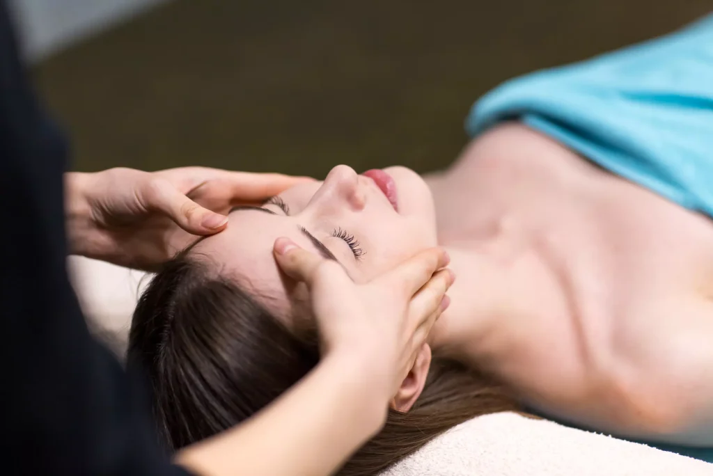 young beautiful woman receiving head face massage beauty spa